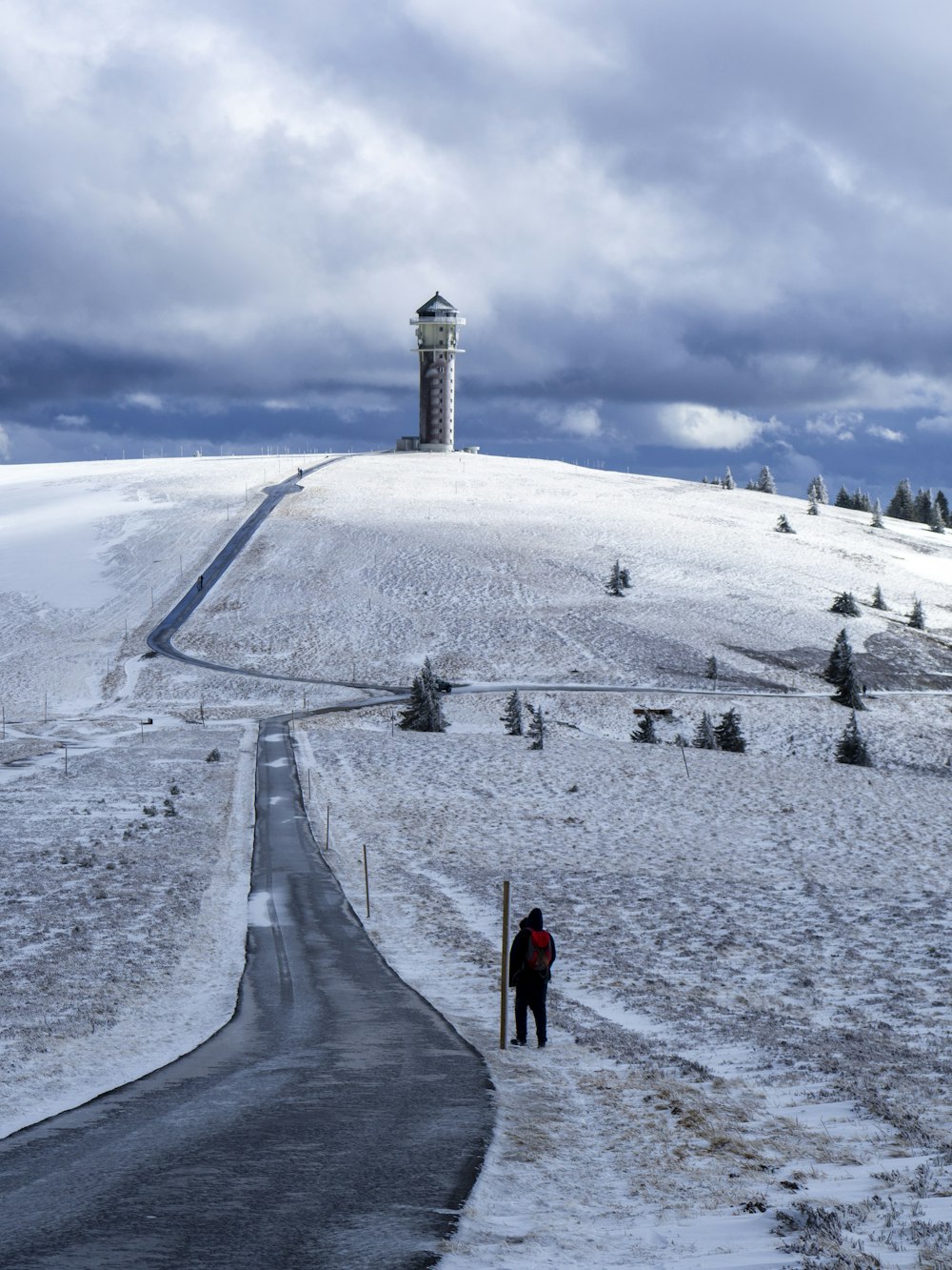 uma pessoa em pé em uma estrada coberta de neve