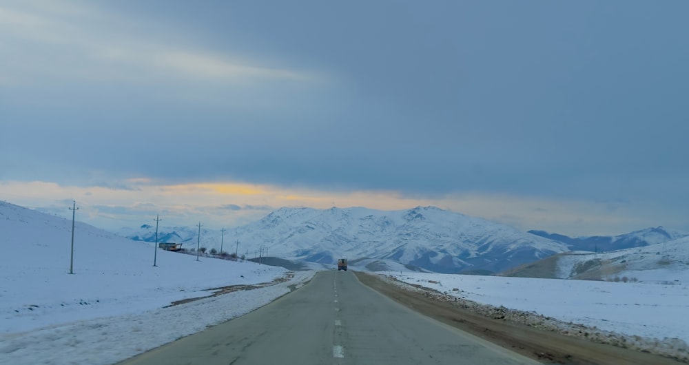 a road with snow covered mountains in the background
