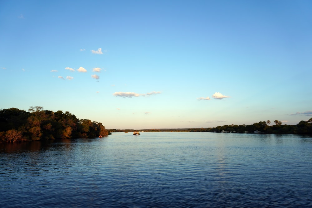 a body of water surrounded by trees and clouds