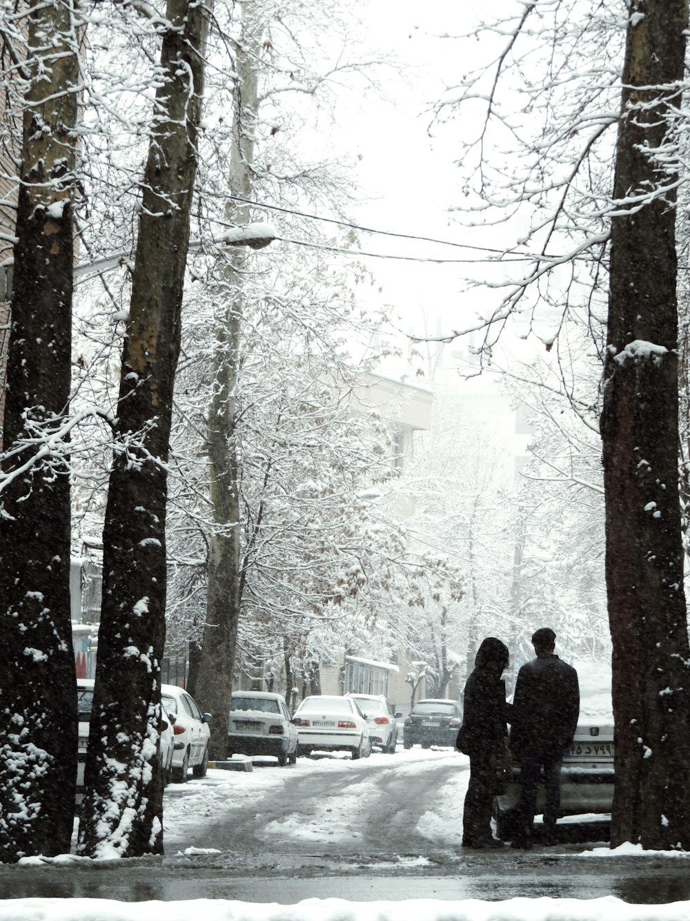 two people standing on a bench in the snow