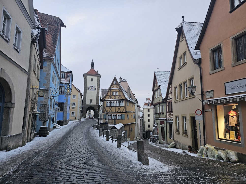 a cobblestone street with buildings and a clock tower in the background