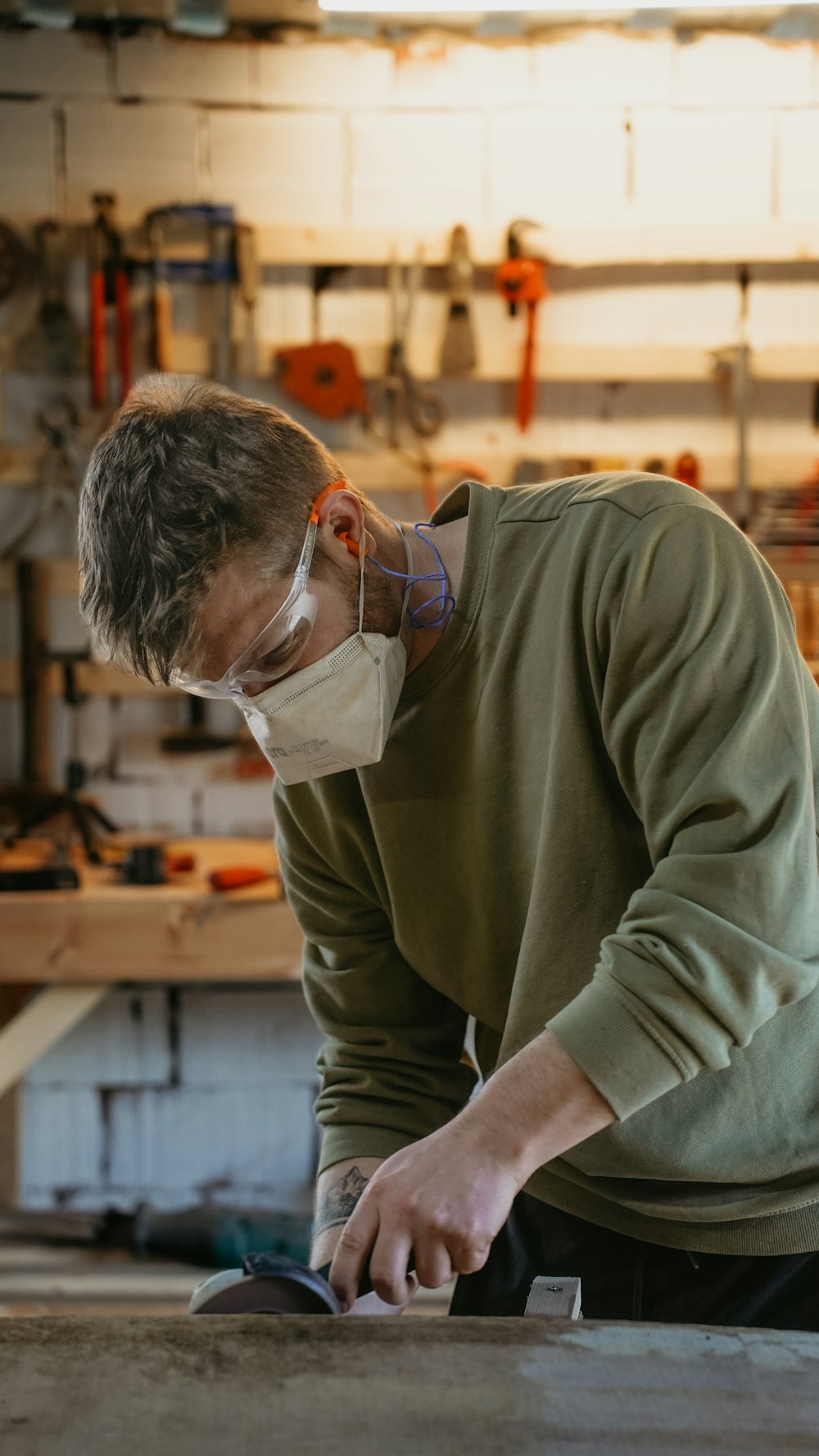 a man wearing a face mask working on a piece of wood