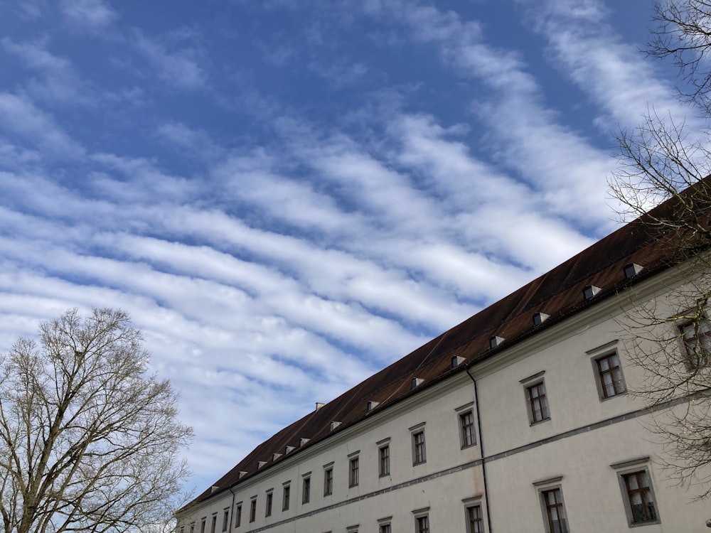 a white building with a brown roof under a cloudy blue sky