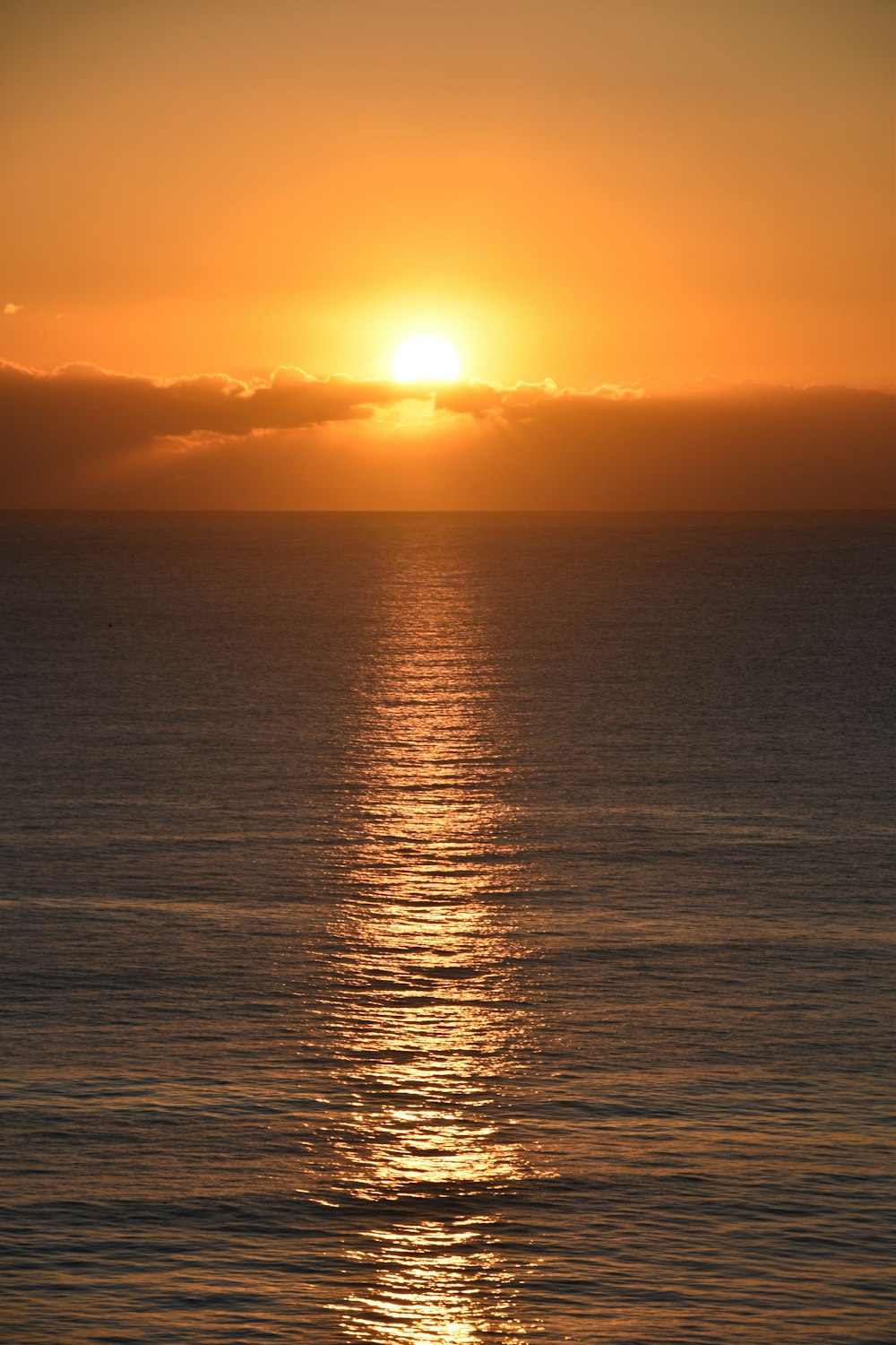 the sun is setting over the ocean on a cloudy day