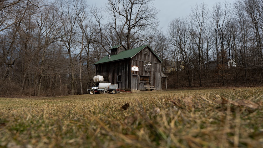 a barn in the middle of a field with a truck parked in front of it