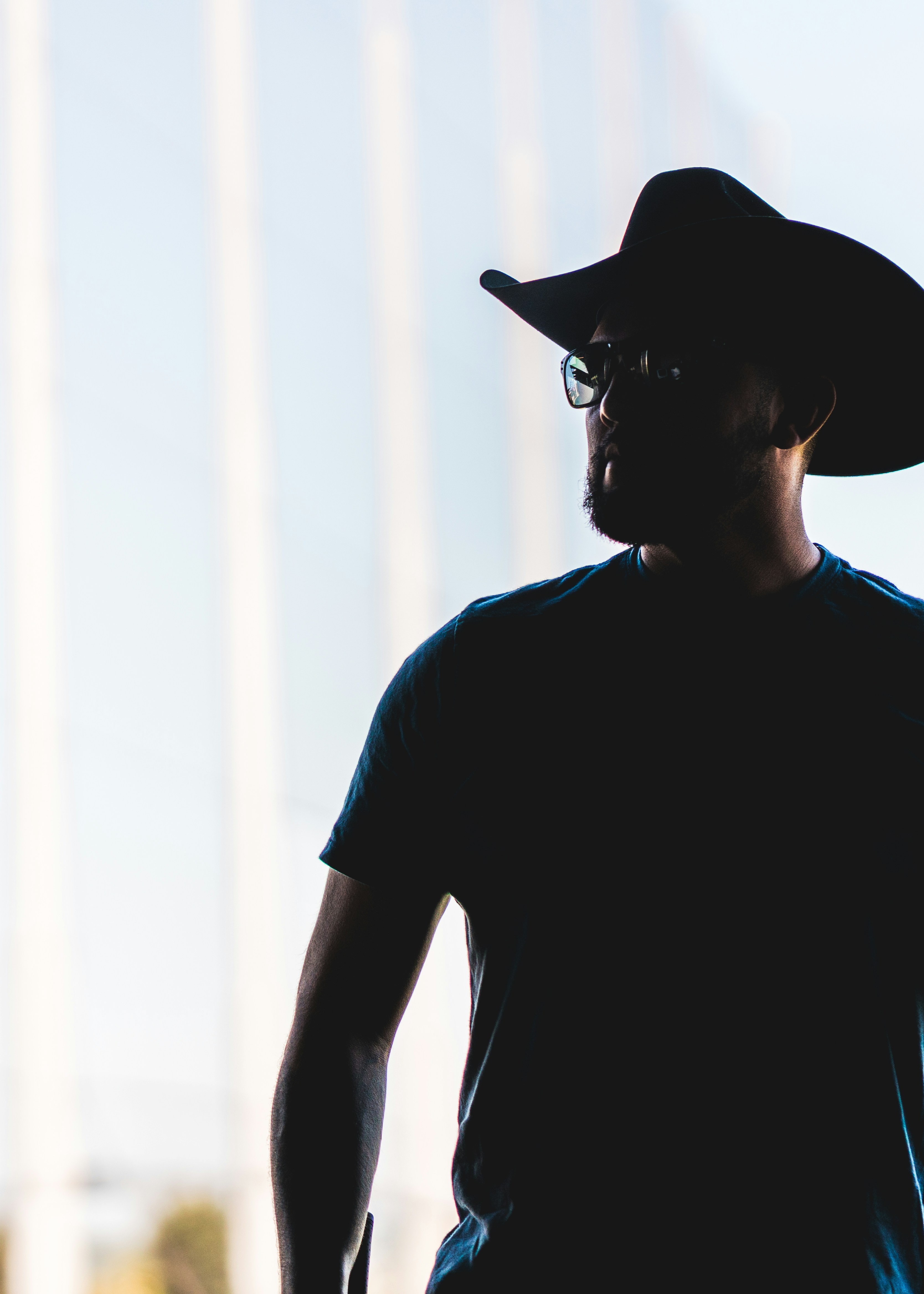 a man wearing a hat and glasses standing in front of a tall building