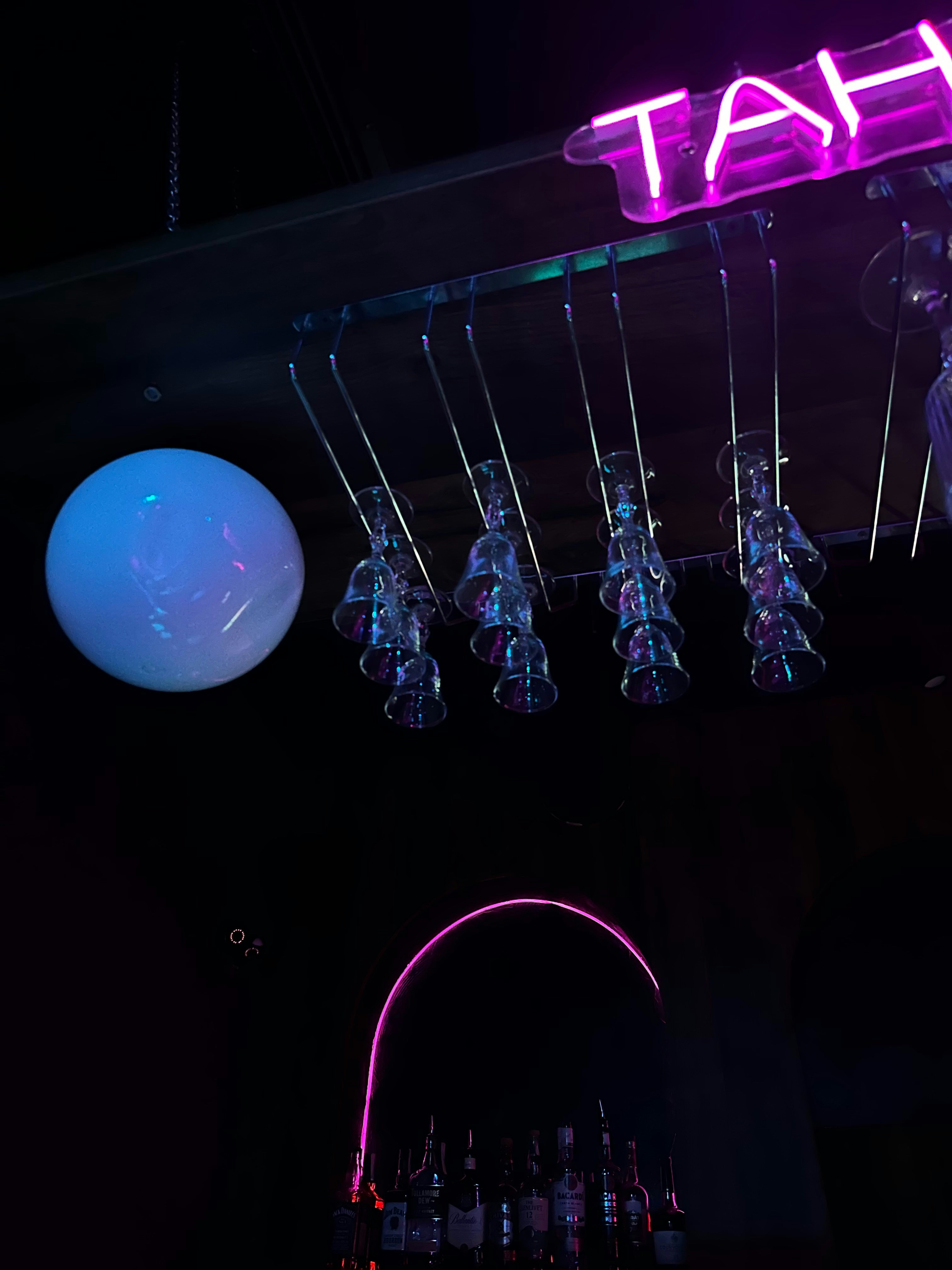 Bar counter with craft beers on tap, dark moody lighting, bartender in background, neon accents