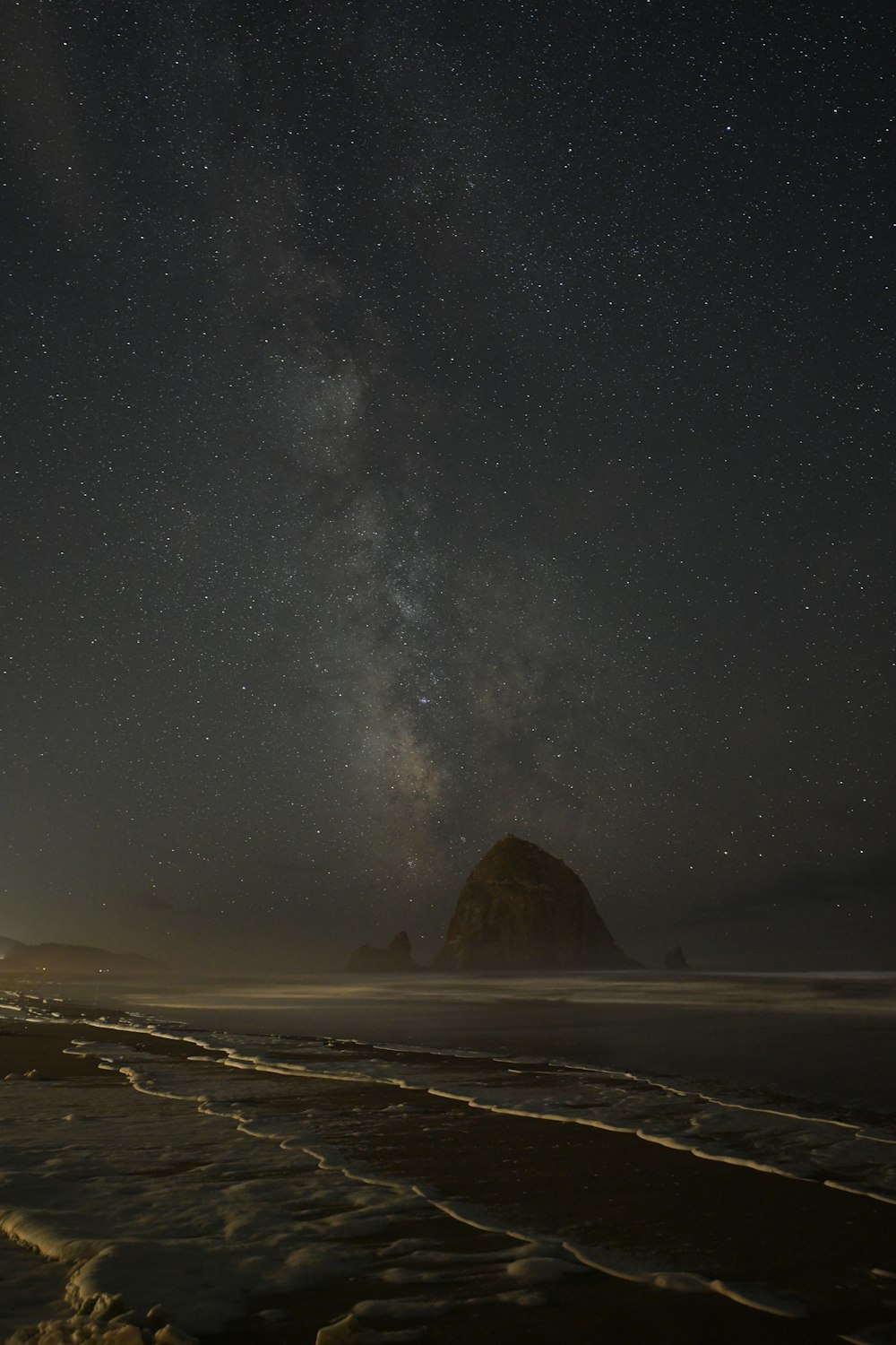 the night sky with stars above the ocean