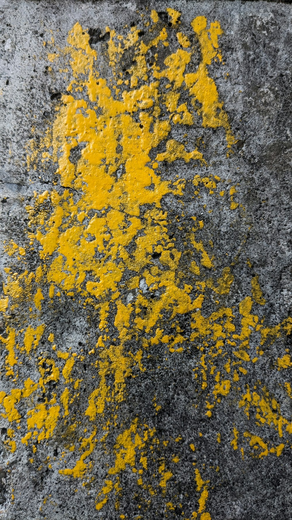 a close up of yellow paint on a cement surface