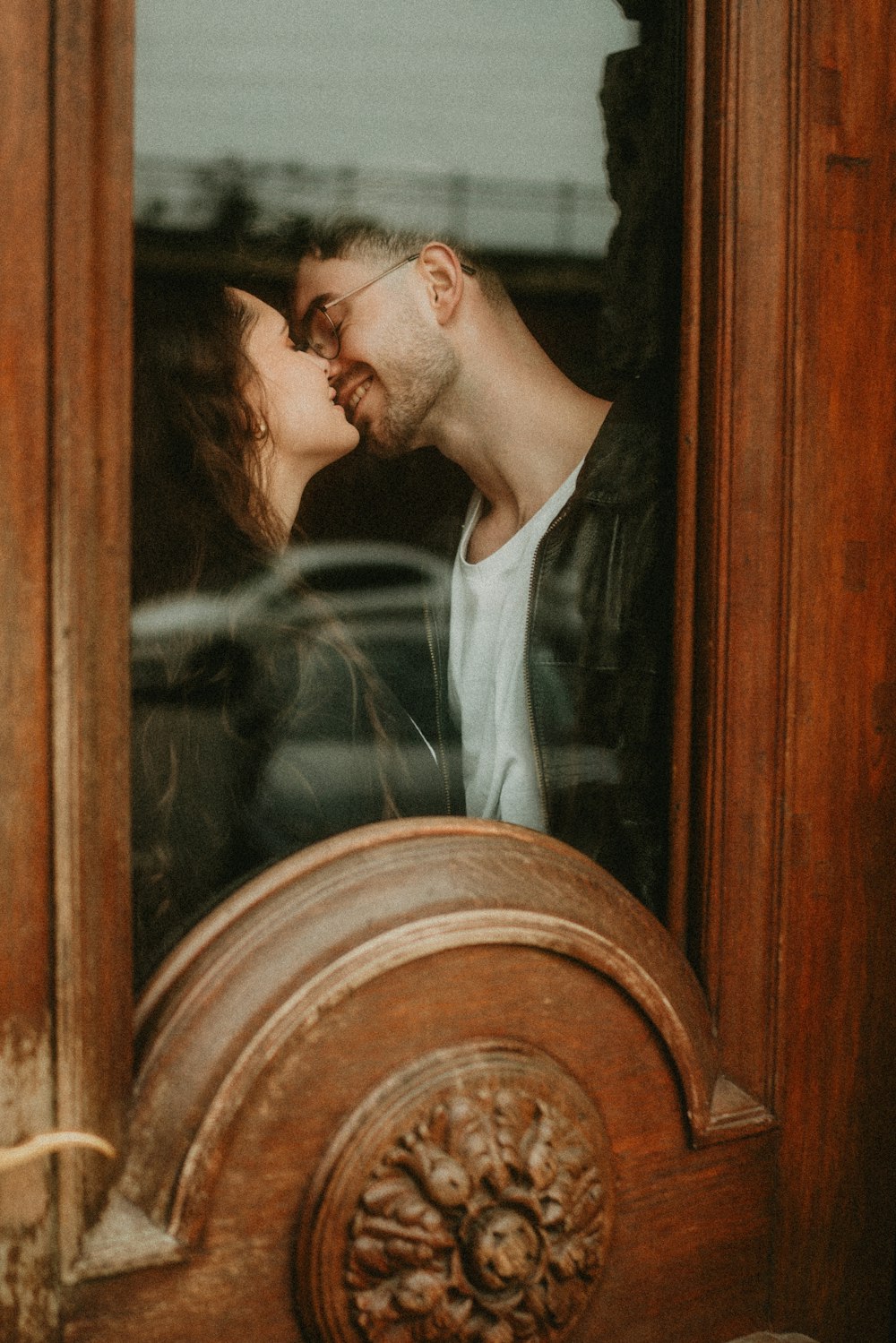a man and a woman kissing in front of a door