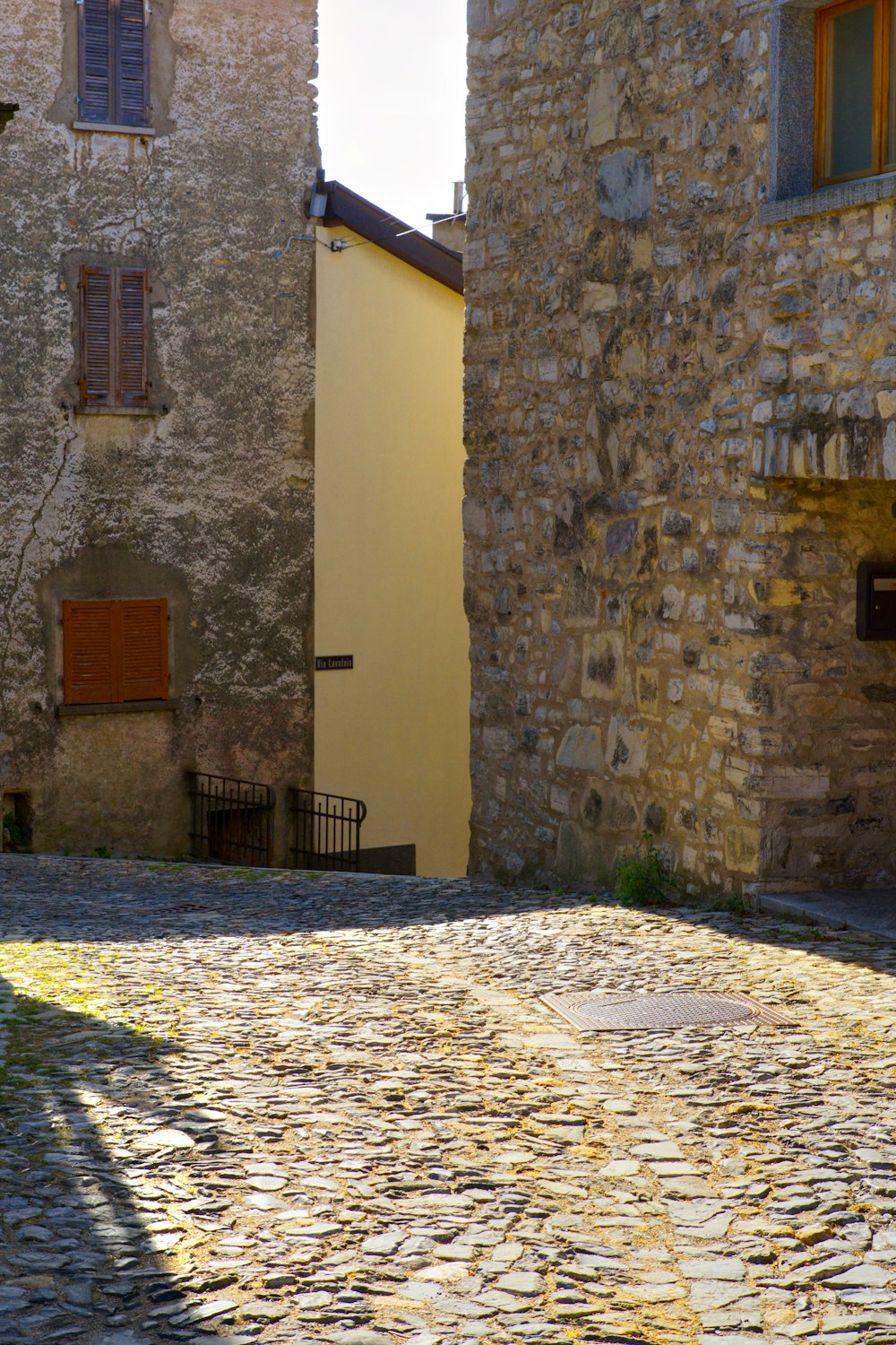 a cobblestone street with a yellow building in the background