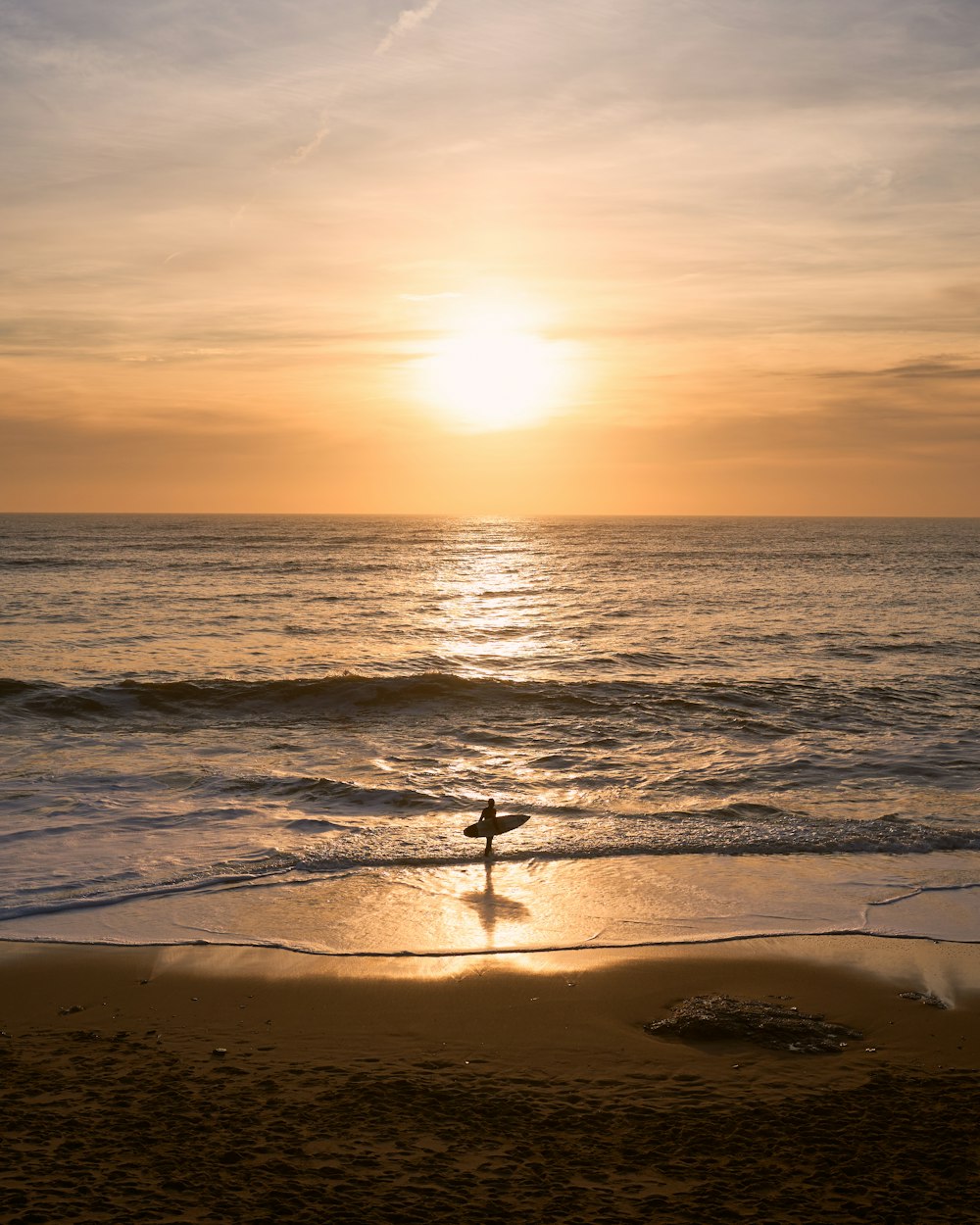 a person standing on a beach holding a surfboard