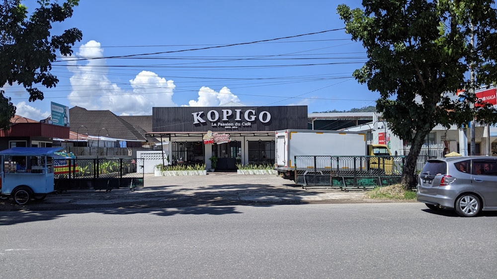 a street view of a kopigo restaurant with cars parked in front of it