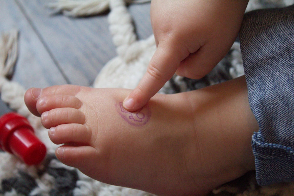 a small child's foot with a red object in the background