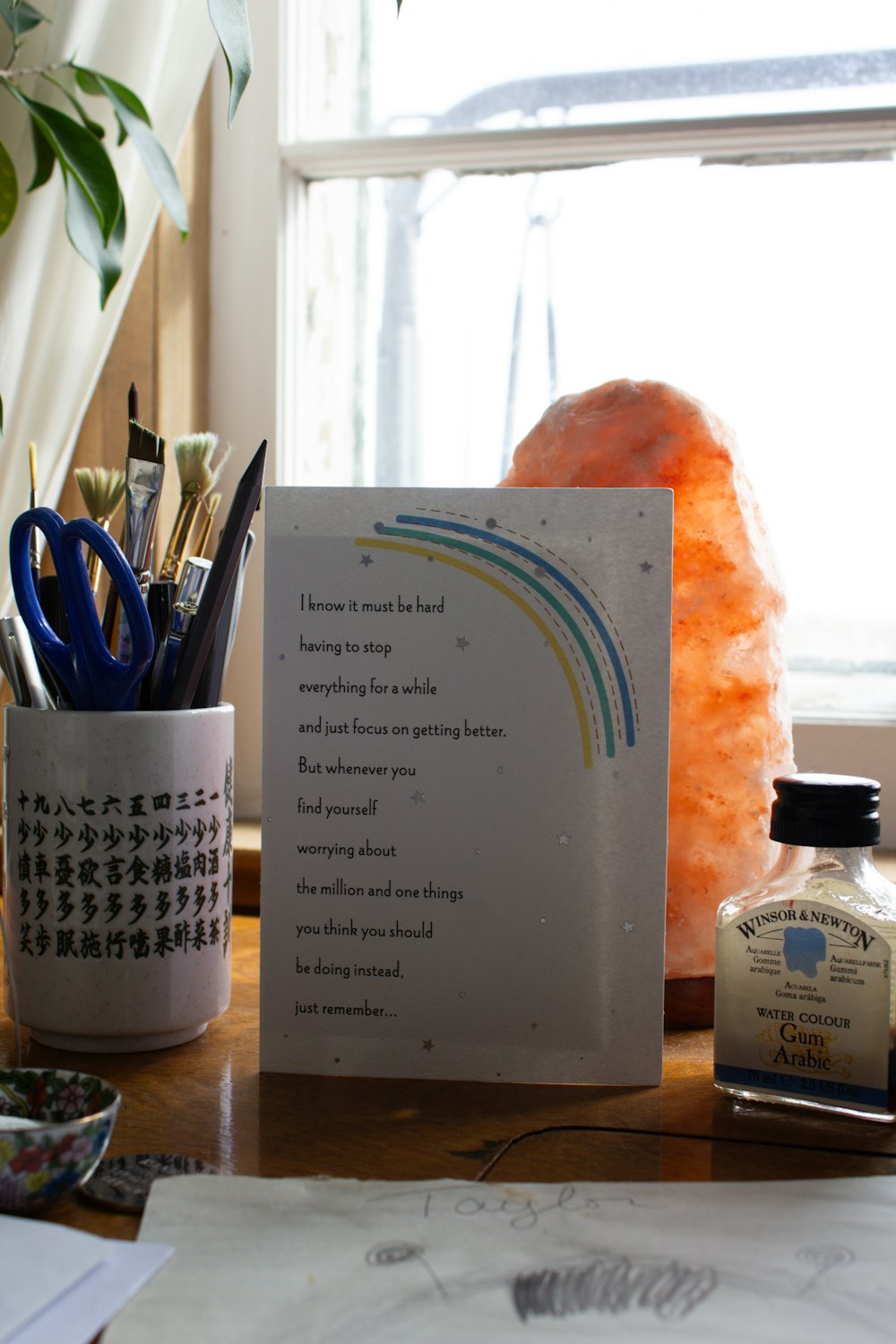 a note sitting on top of a desk next to a potted plant