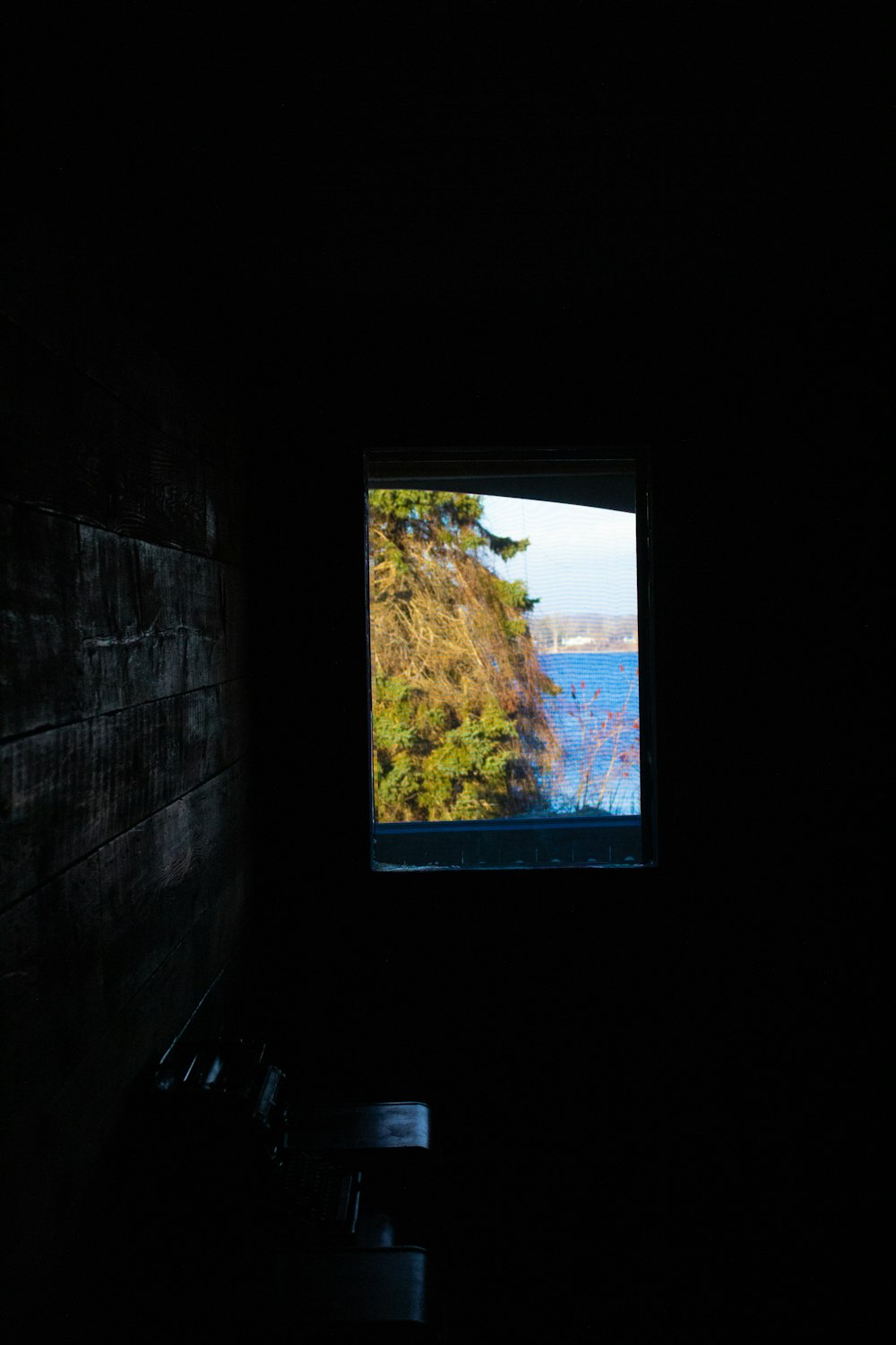 a window in a dark room with a view of a lake