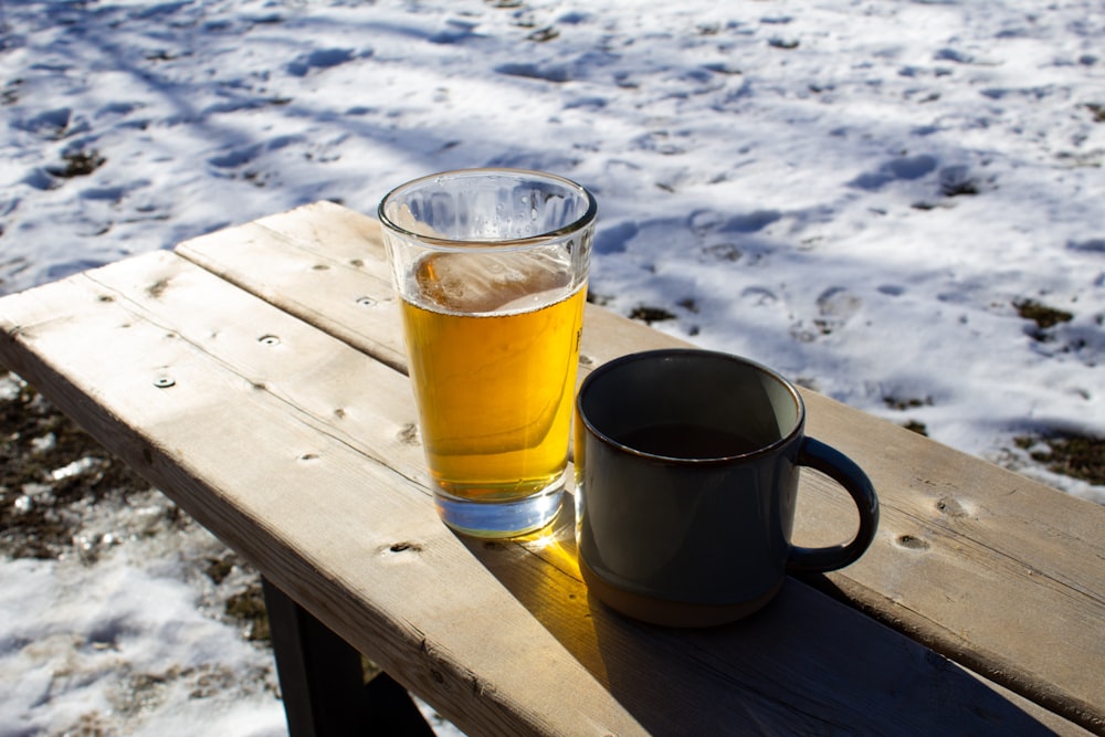 a glass of beer sitting on top of a wooden table