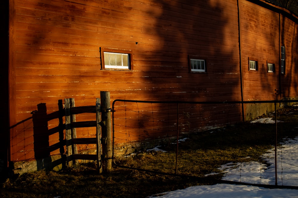 a red barn with a fence and snow on the ground