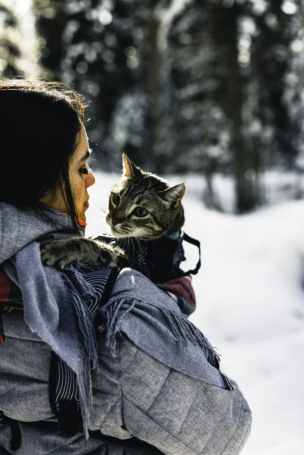 uma mulher segurando um gato em seus braços na neve