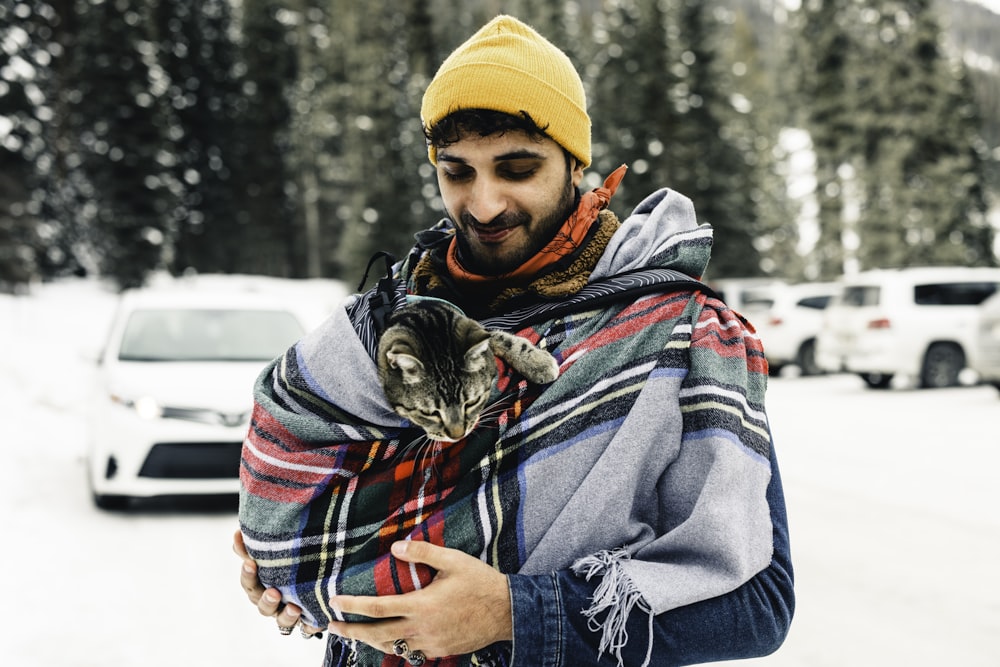 a man holding a cat wrapped in a blanket