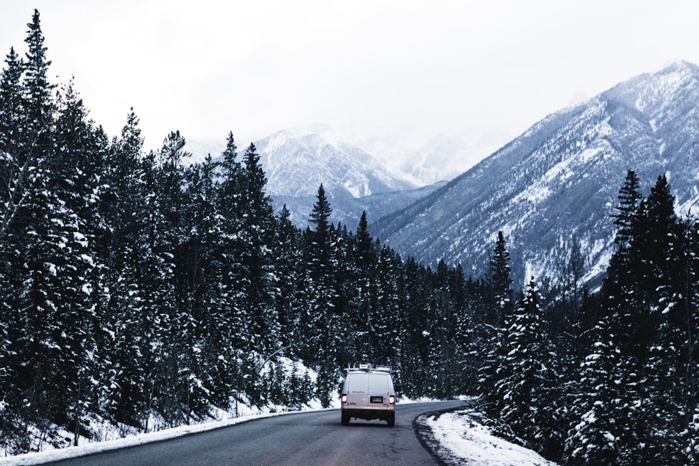 a car driving down a snowy road in the mountains