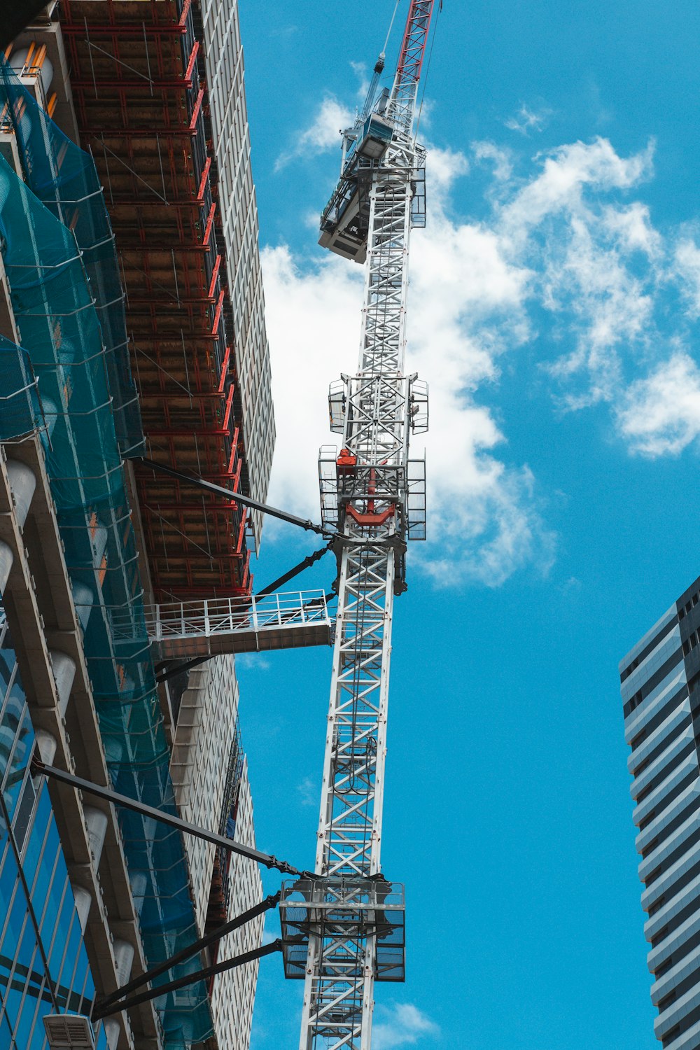 a crane is standing next to a tall building