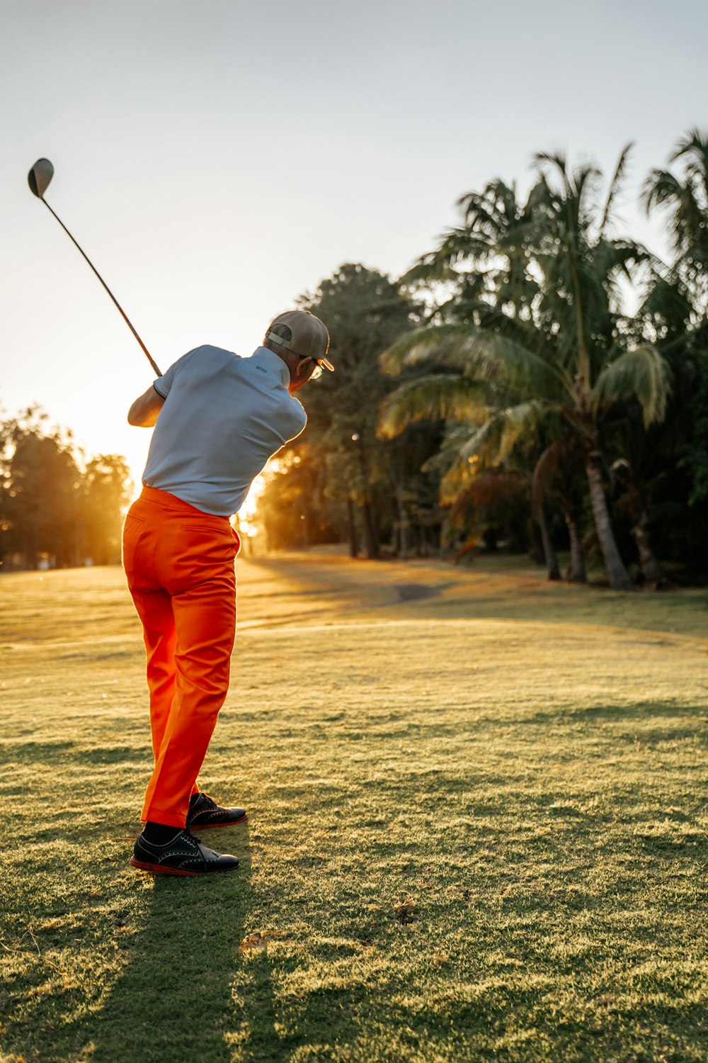 a man swinging a golf club on top of a lush green field