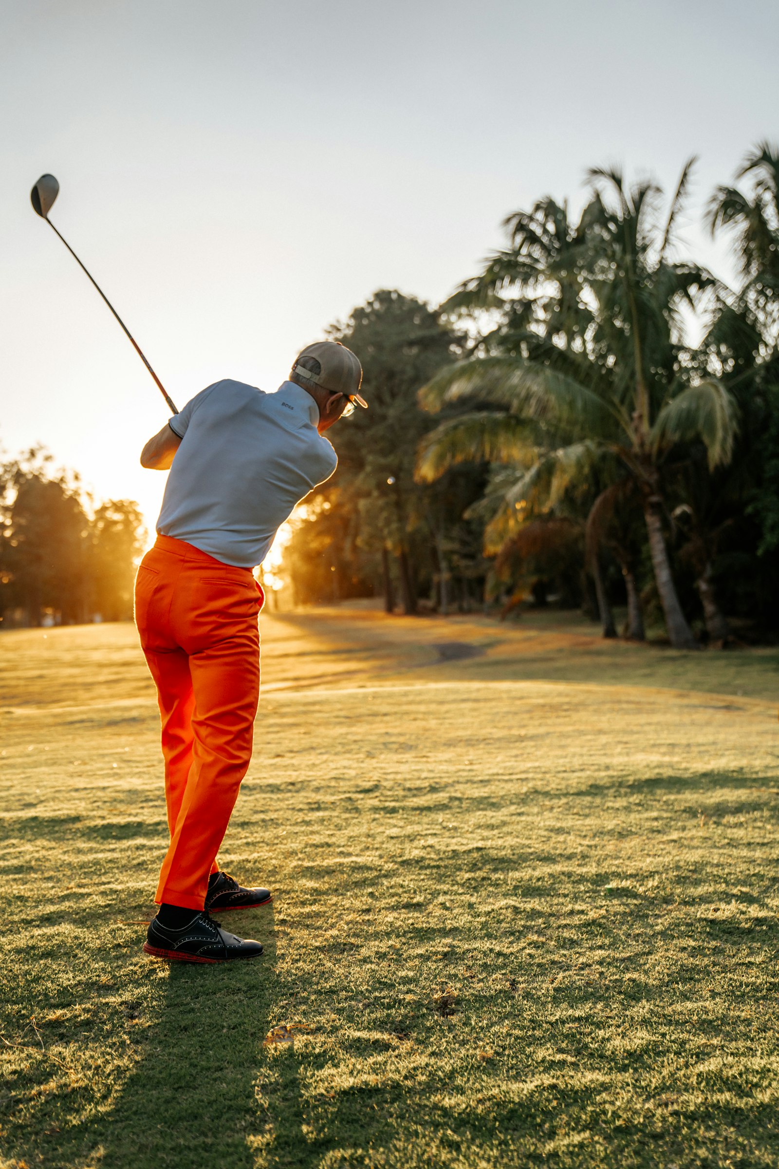 Golfer mid-swing on a sunlit fairway — back-nine cramps hit hardest after four hours under the sun.