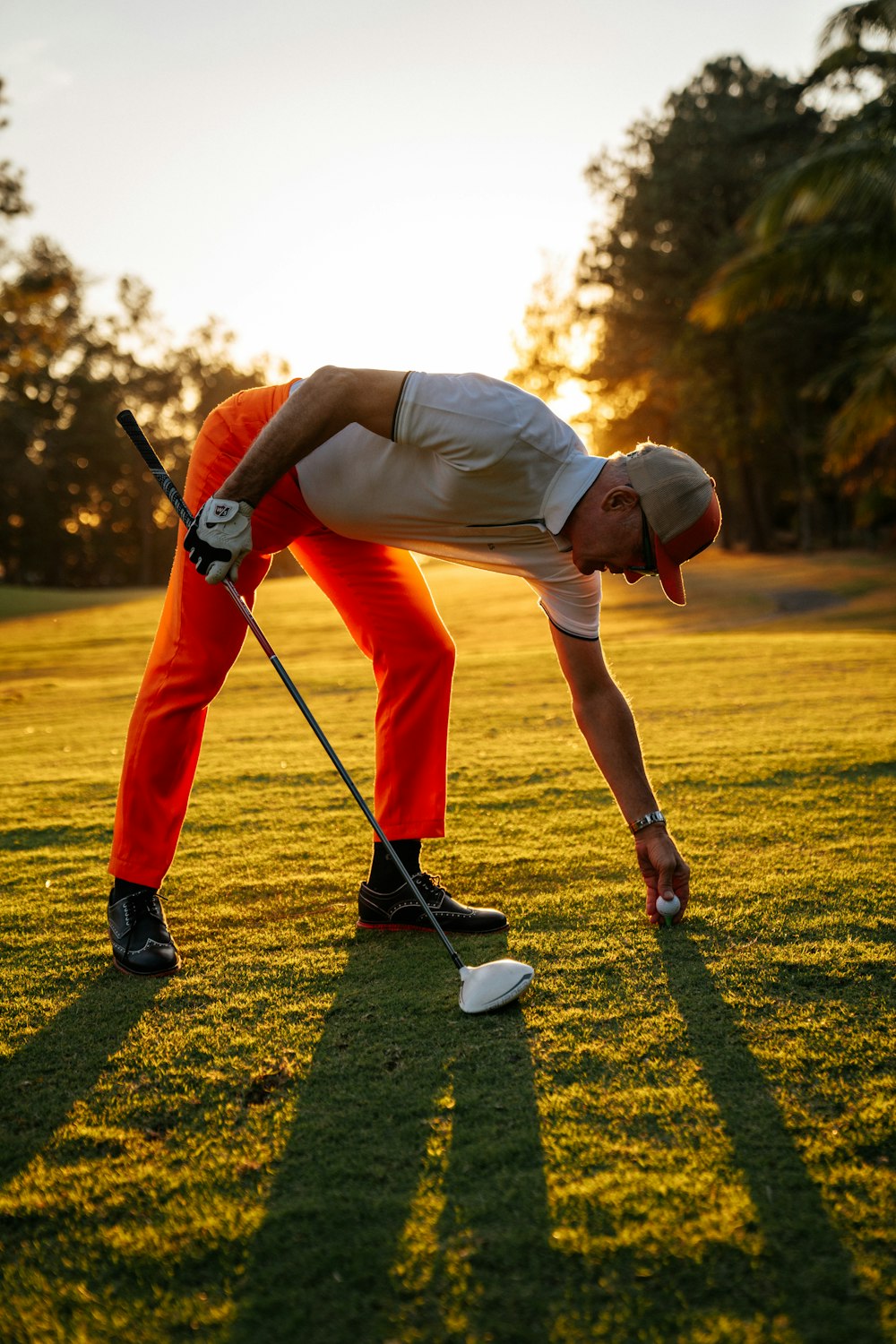 a man bending over to pick up a golf ball