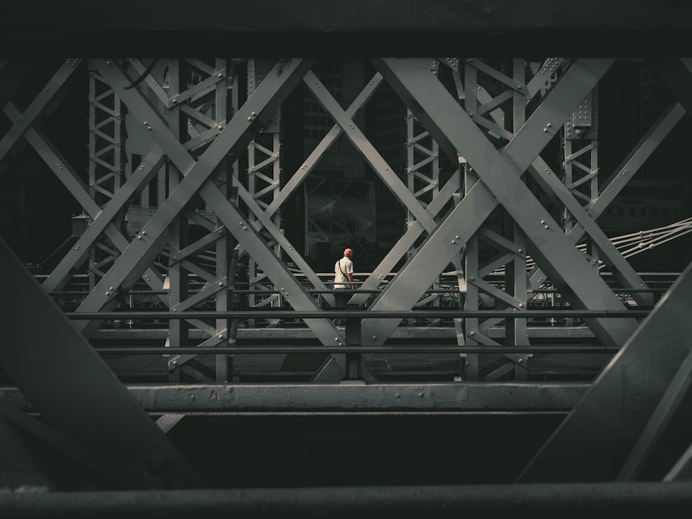 a man walking across a bridge over water