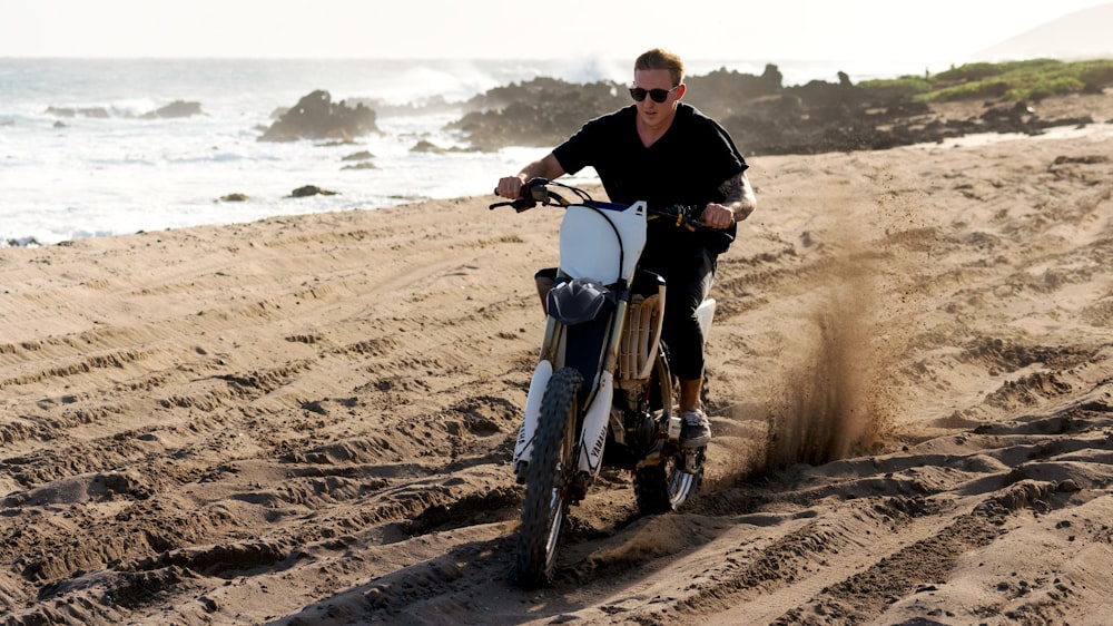 a man riding a bike down a sandy beach