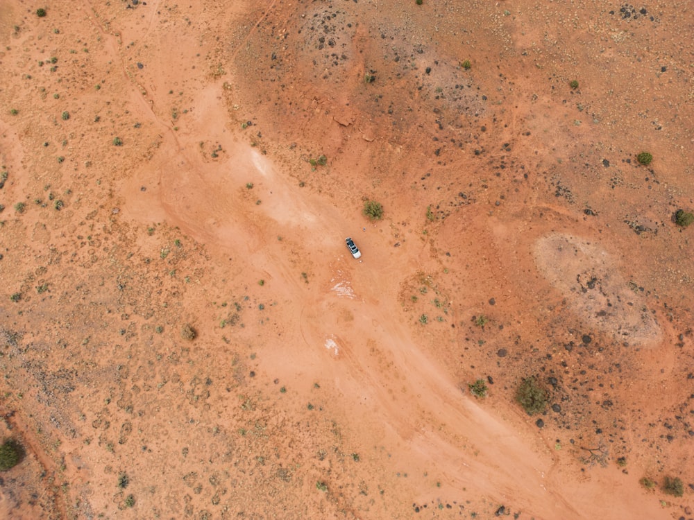 an aerial view of a dirt field with trees