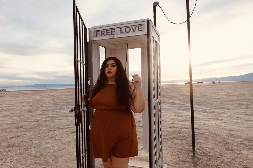 a woman in a brown dress standing in a phone booth
