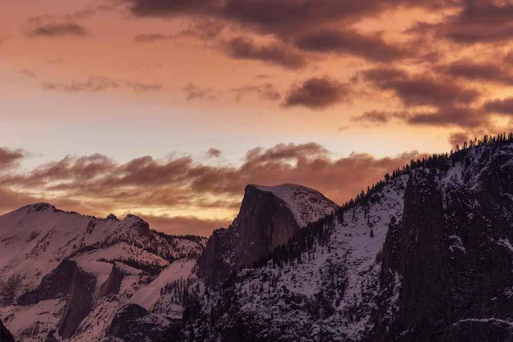 a mountain covered in snow under a cloudy sky