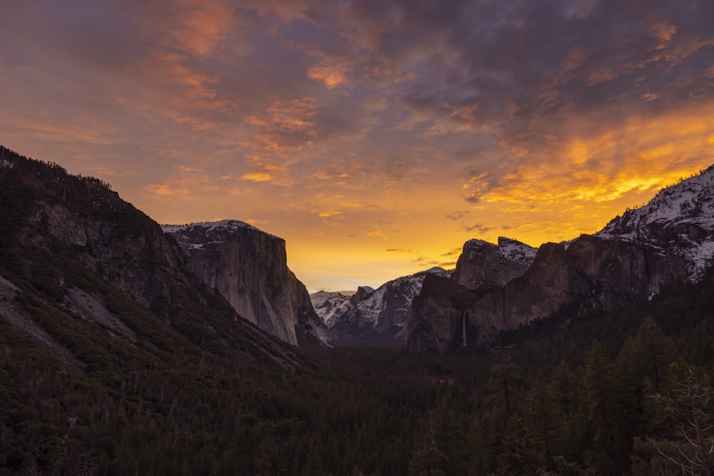 the sun is setting over the mountains in the valley