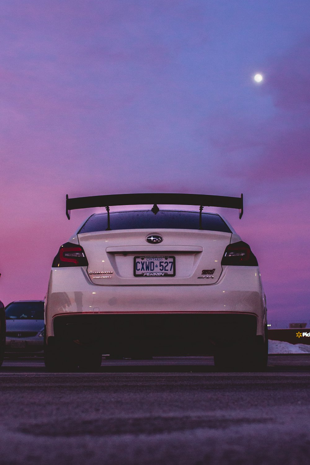 a white car parked in front of a purple sky