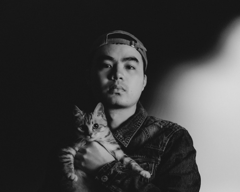 a black and white photo of a man holding a cat