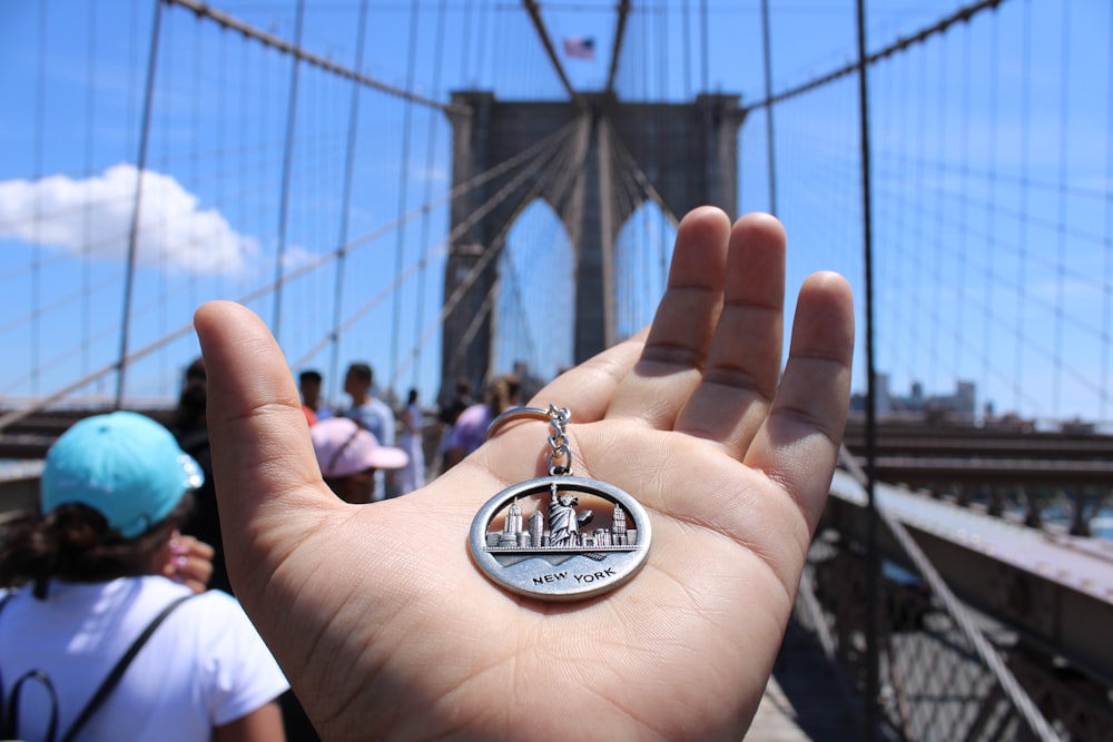 a person holding a key chain in front of a bridge