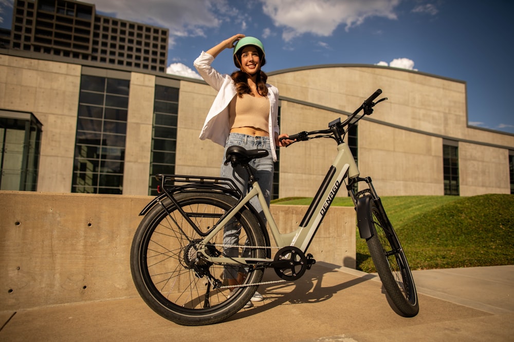 a woman standing next to a bike in front of a building