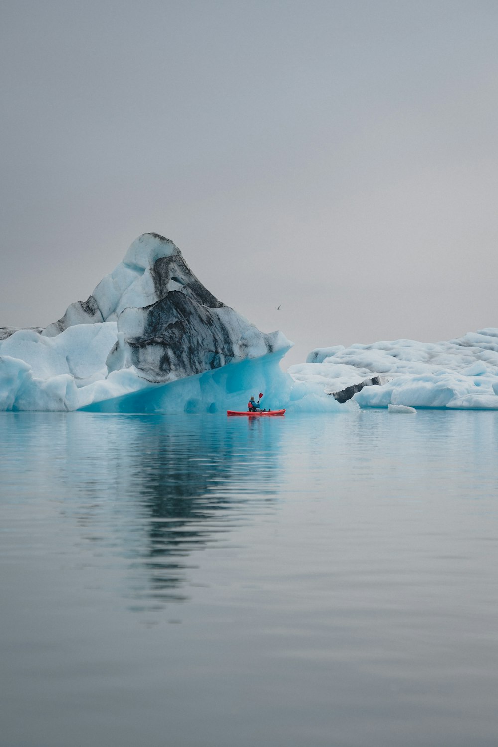 a person in a kayak in front of an iceberg