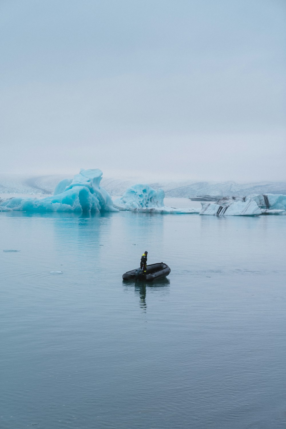 Ein Mann auf einem Boot im Wasser in der Nähe von Eisbergen