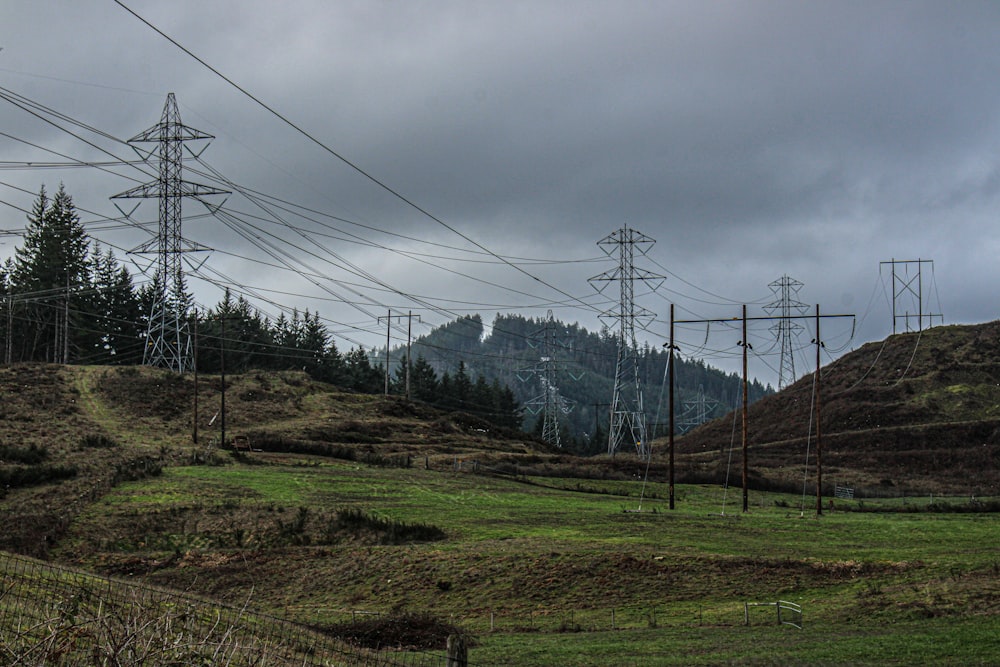 a field with power lines and a mountain in the background
