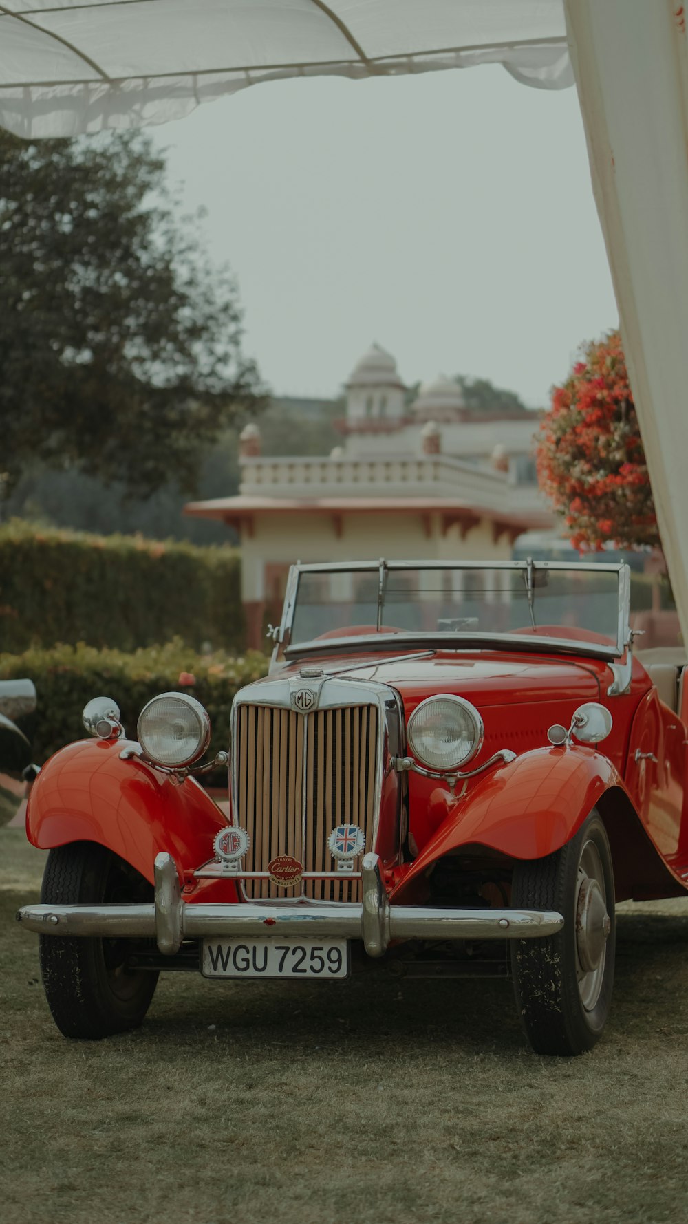 an old red car is parked under a canopy