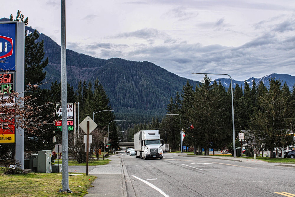 a truck driving down a street next to a forest