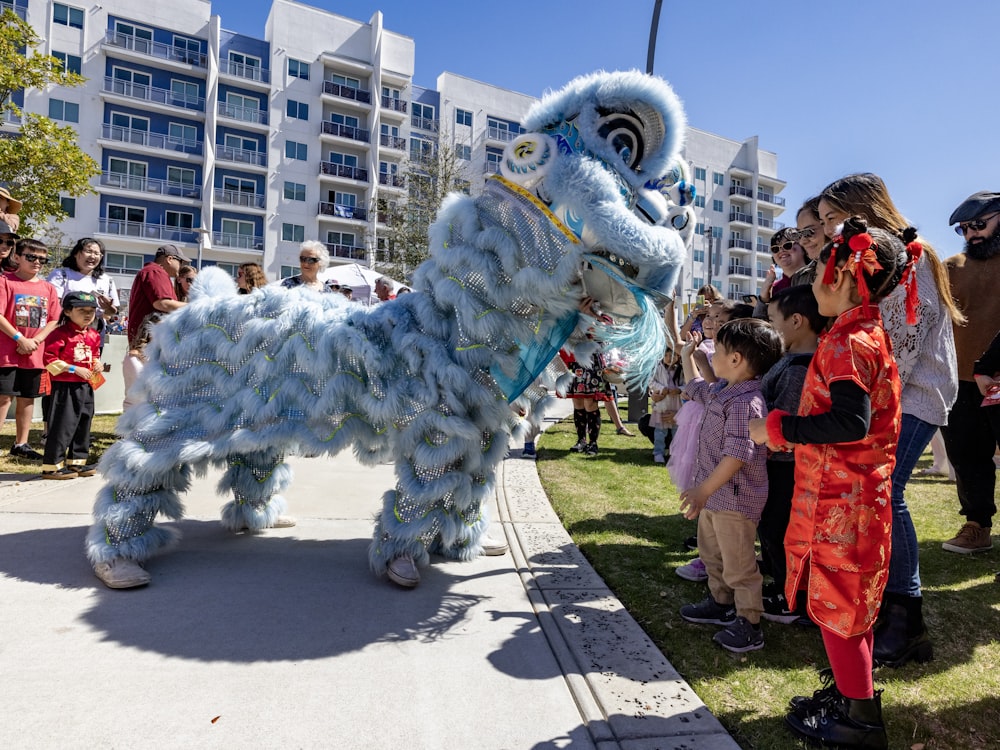 a group of people standing around a blue and white lion