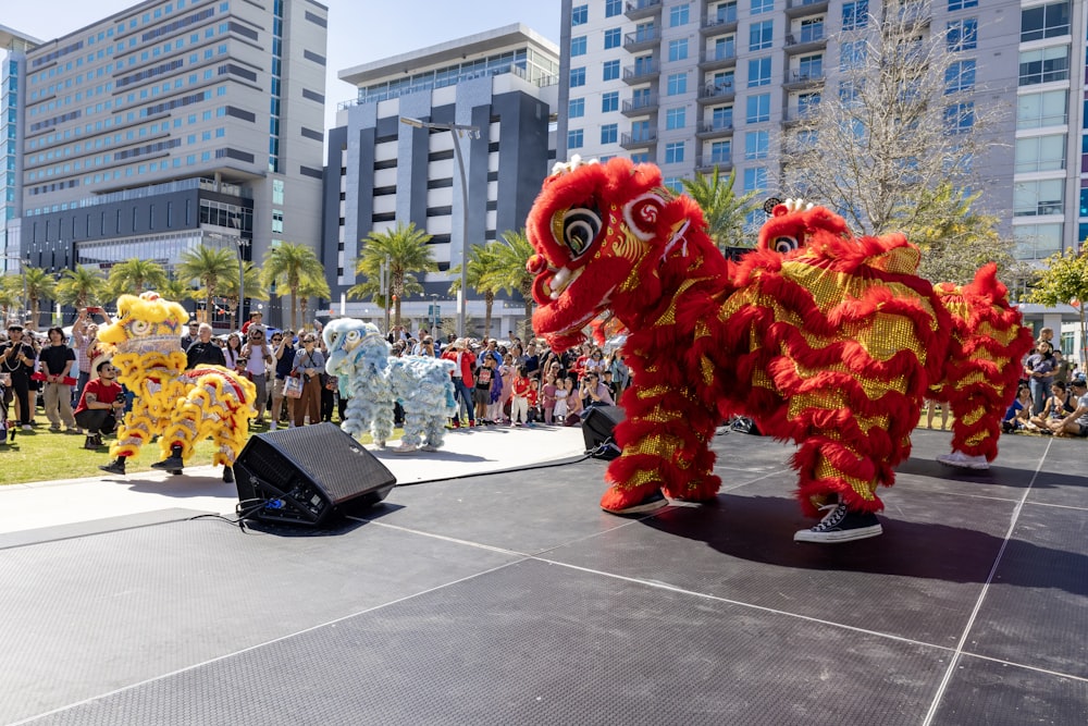 a group of people standing next to two red and yellow lions