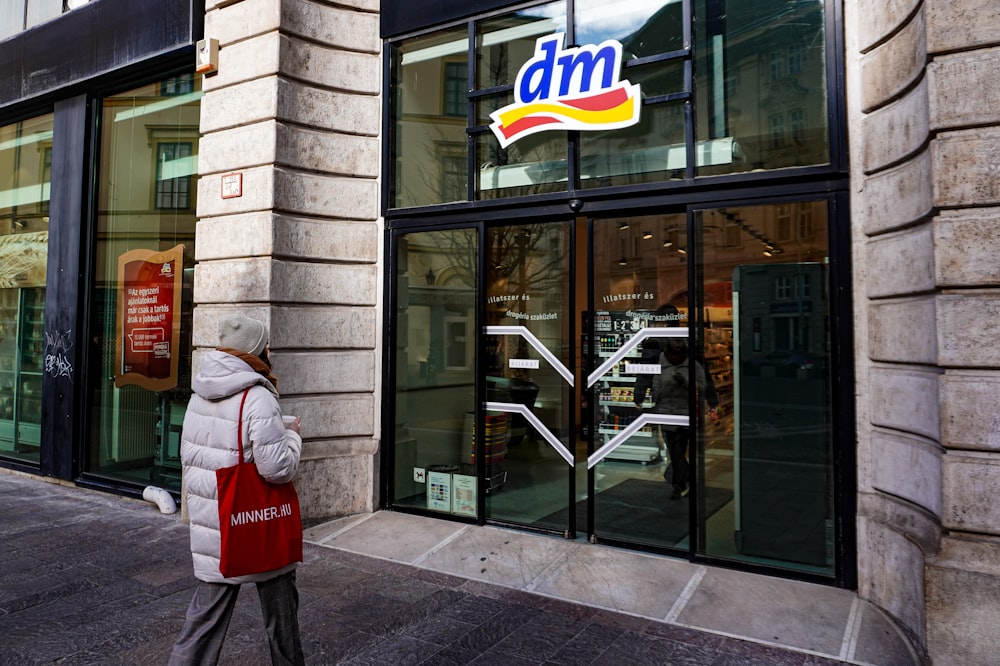 a woman walking down a street past a store front