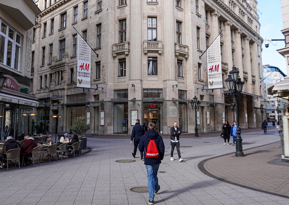 a group of people walking down a street next to tall buildings