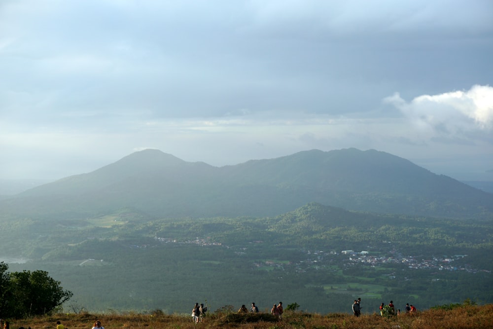 a group of people standing on top of a lush green hillside