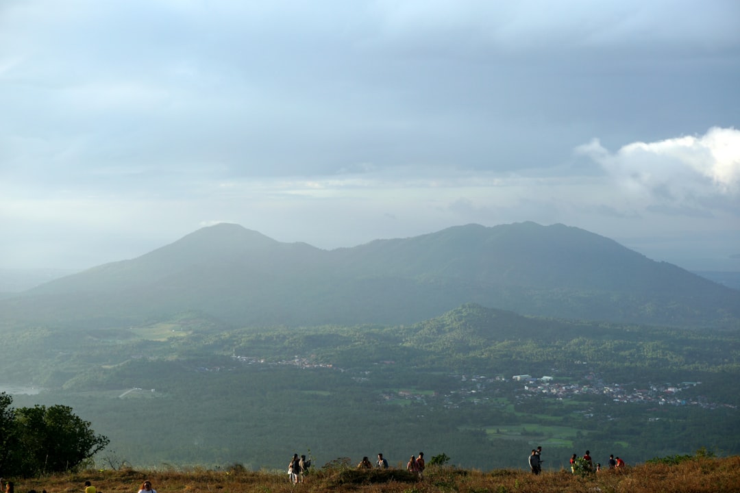a group of people standing on top of a lush green hillside,